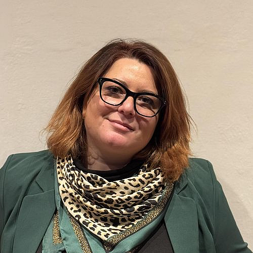 Porträt einer Frau Porträt einer lächelnden Frau mit Brille und Leoparden-Schal vor neutralem Hintergrund.