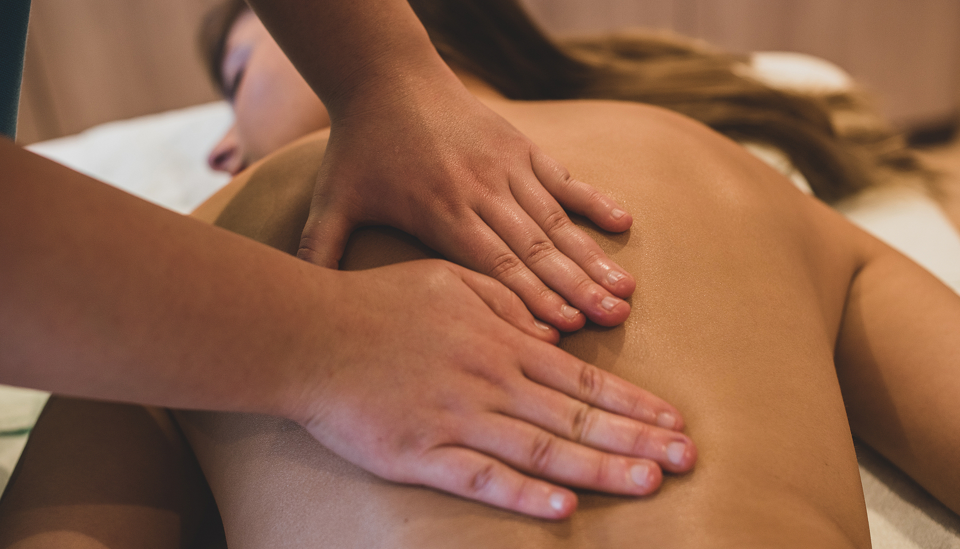 Entspannende Rückenmassage Nahaufnahme von Händen, die den Rücken einer Frau massieren.