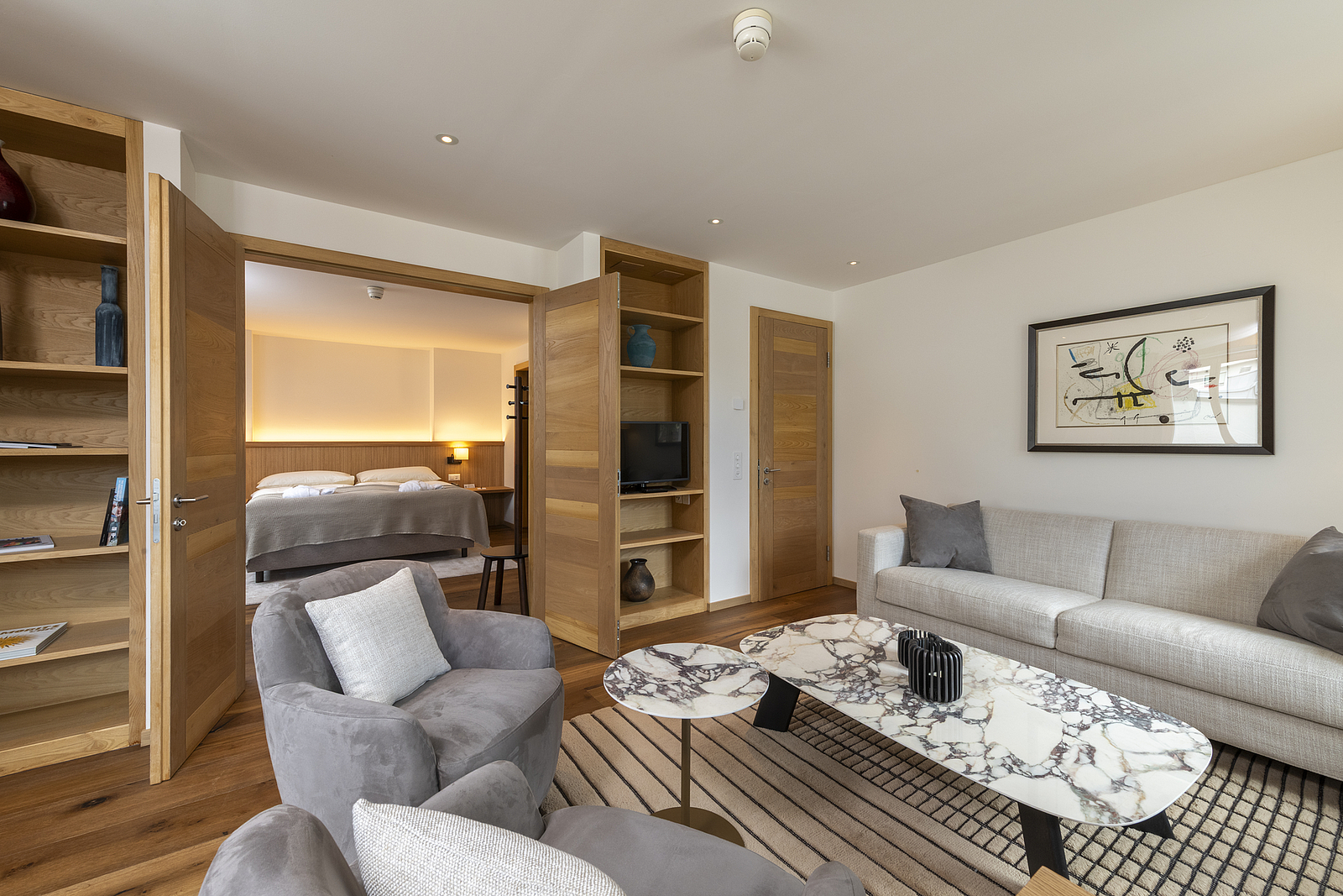 Moderne Hotelsuite mit Wohnbereich und Schlafzimmerblick.