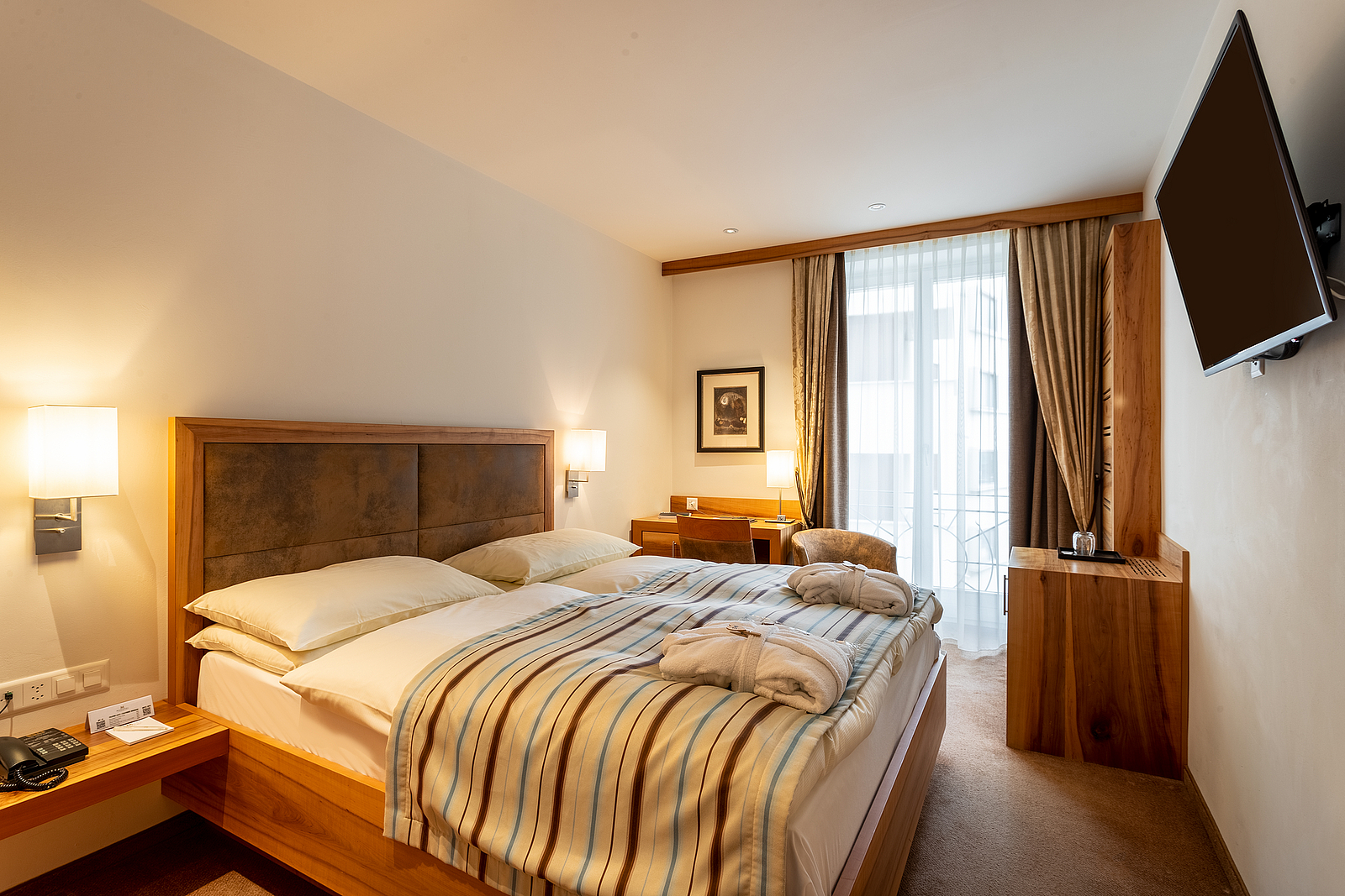 Gemütliches modernes Hotelzimmer mit Doppelbett und Holzmöbeln.