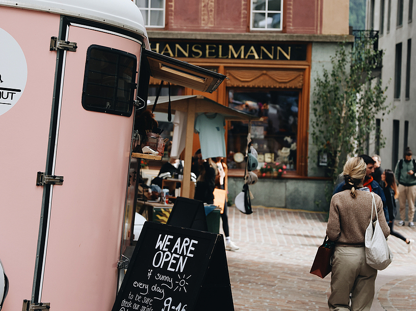 Rosa Imbisswagen in europäischer Gasse Rosa Imbisswagen mit einem Öffnungsschild in einer historischen Gasse.