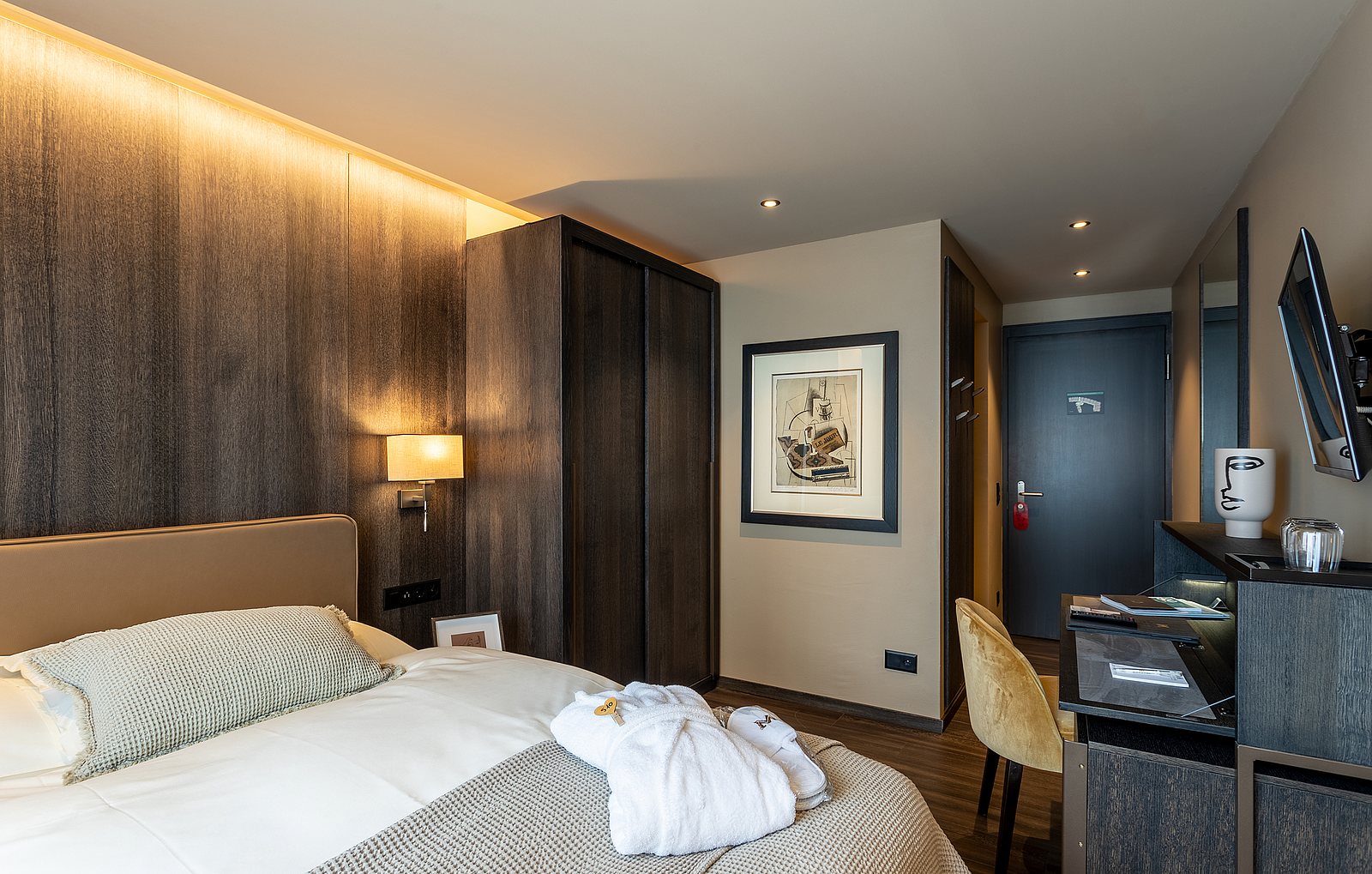 Modernes Hotelzimmer mit bequemem Bett, dunkler Holzverkleidung und Schreibtisch.