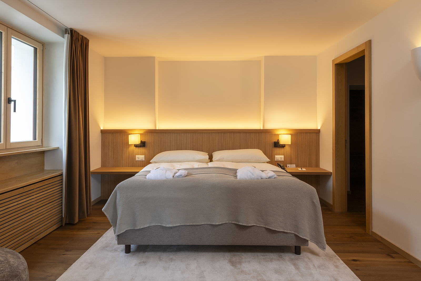 Gemütliches Hotelzimmer mit ordentlich gemachtem Bett und warmem Licht.