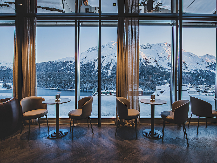 Lounge mit großen Fenstern und Blick auf schneebedeckte Berge.