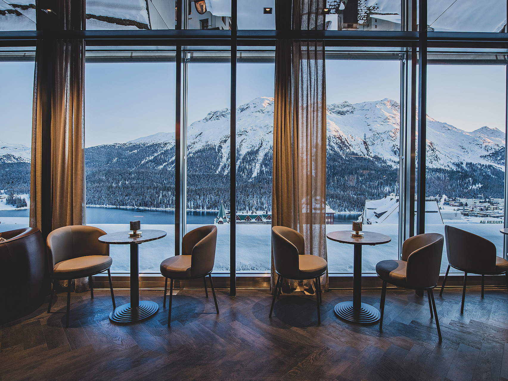 Alpenblick aus Luxus-Lounge Lounge mit großen Fenstern und Blick auf schneebedeckte Berge.