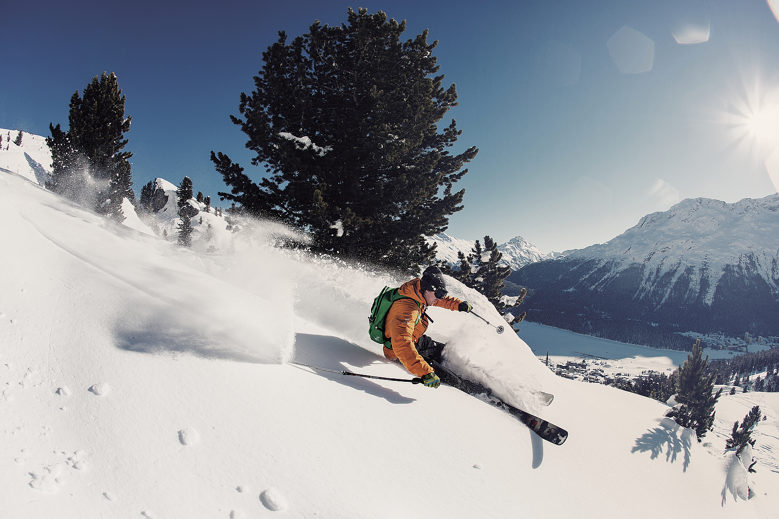 Skifahrer in orangefarbener Jacke beim Freeriden im Schnee