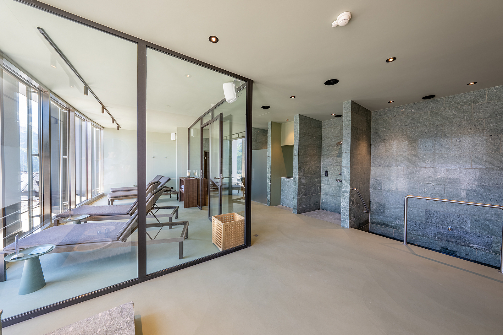 Modernes Spa-Interieur mit glasumschlossenem Ruheraum und Steinduschen.