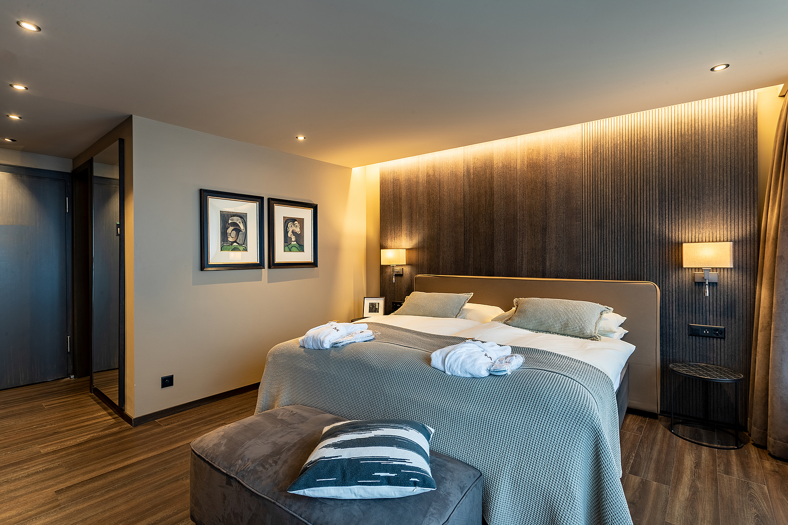 Gemütliches Hotelzimmer mit warmer Beleuchtung und grauem Bett