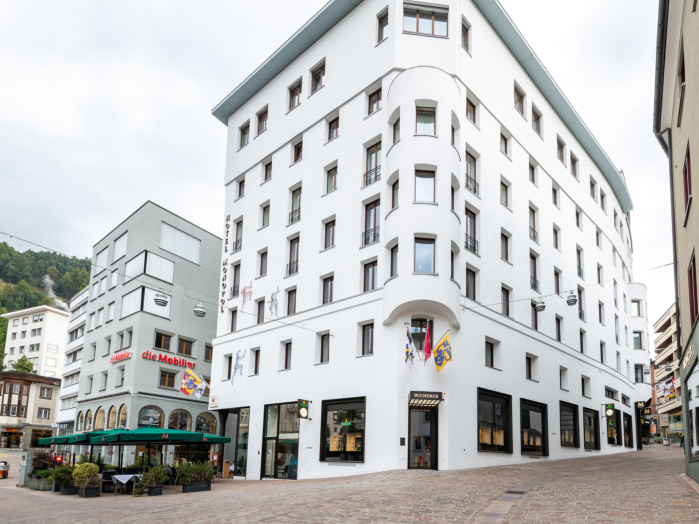 Weisses Hotelgebäude in St. Moritz Ein grosses, weisses Hotelgebäude mit geschwungener Architektur und Geschäften im Erdgeschoss in St. Moritz.