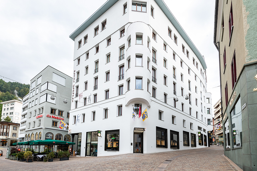 Ein grosses, weisses Hotelgebäude mit geschwungener Architektur und Geschäften im Erdgeschoss in St. Moritz.