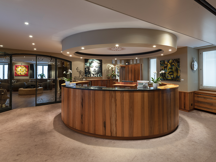 Geschwungene Hotelrezeption aus Holz in einer warm beleuchteten Lobby.