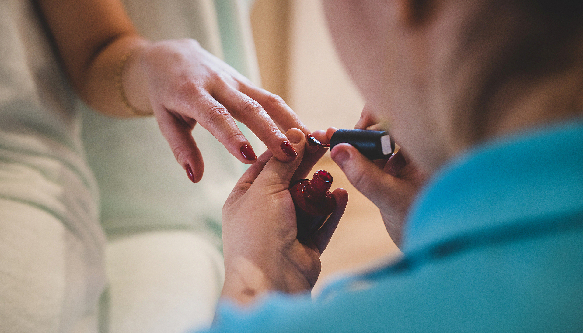Maniküre beim Nägelackieren Maniküre trägt roten Nagellack auf die Fingernägel einer Kundin auf