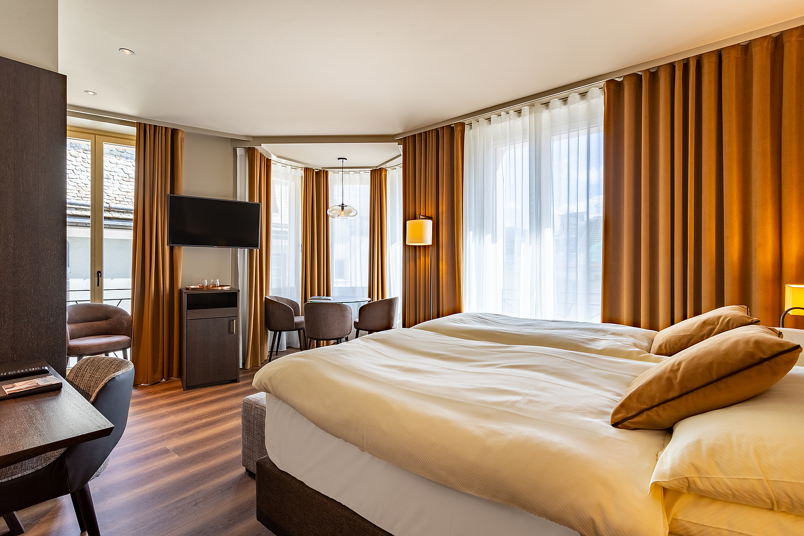 Modernes Hotelzimmer mit Doppelbett und orangen Vorhängen.
