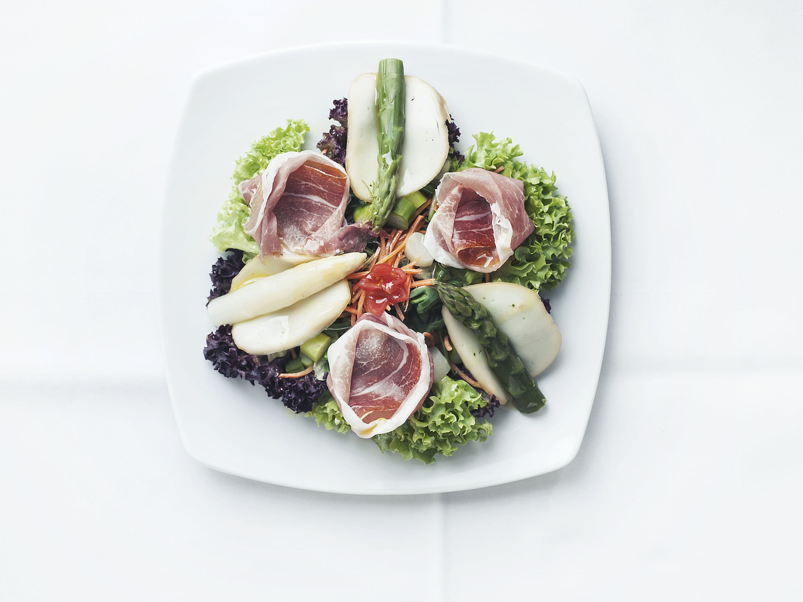 Gourmetsalat mit Spargel und Schinken auf weißem Teller