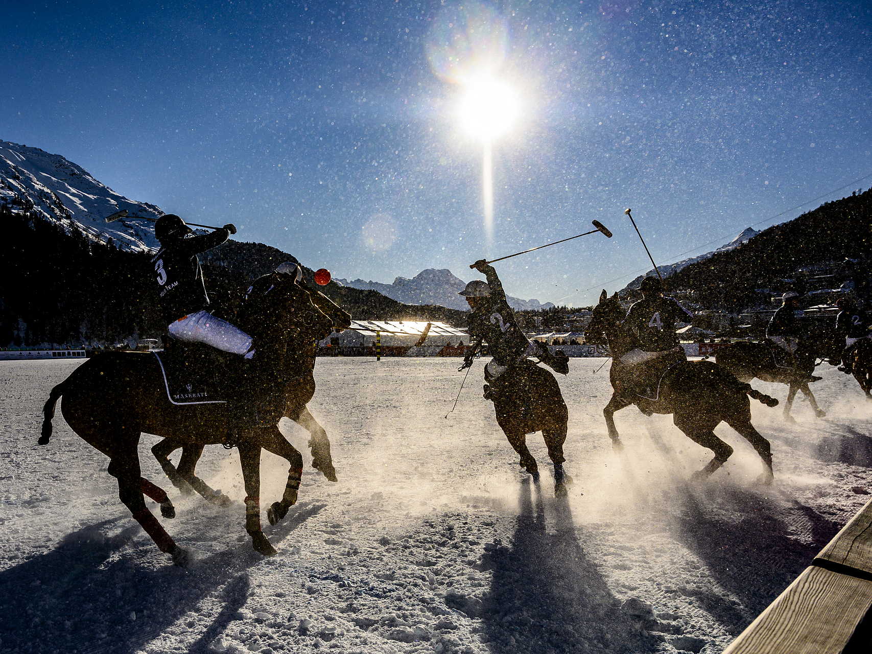 Snow-Polo-Spiel in St. Moritz Polospieler zu Pferd bei einem Schneespiel mit heller Sonne im Hintergrund.