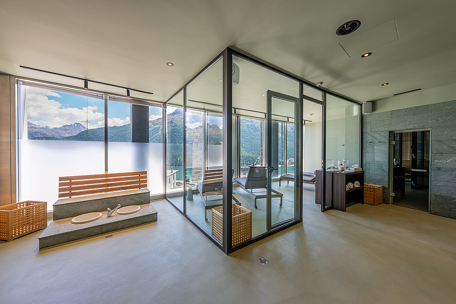 Moderner Wellnessbereich mit Fußbad und Glas-Sauna mit Bergblick.