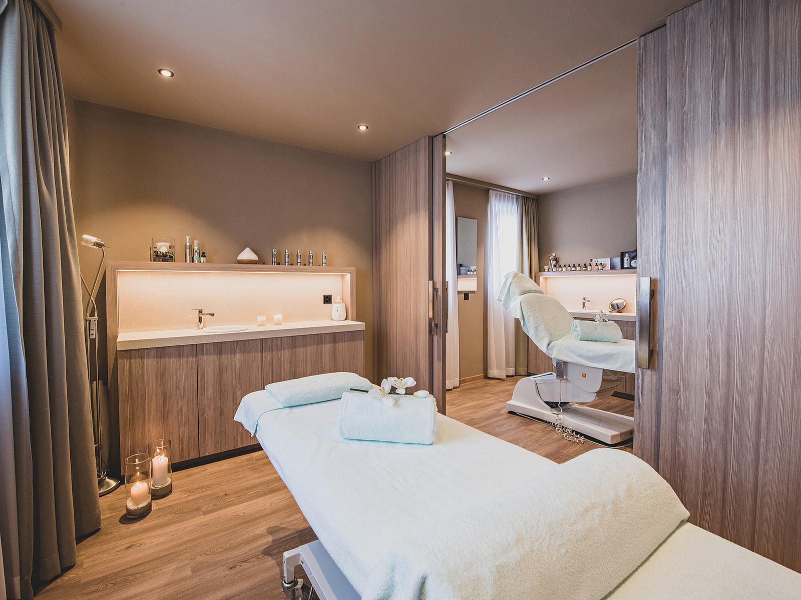 Moderner Spa-Raum mit Massagebett, Waschbecken und warmer Beleuchtung.