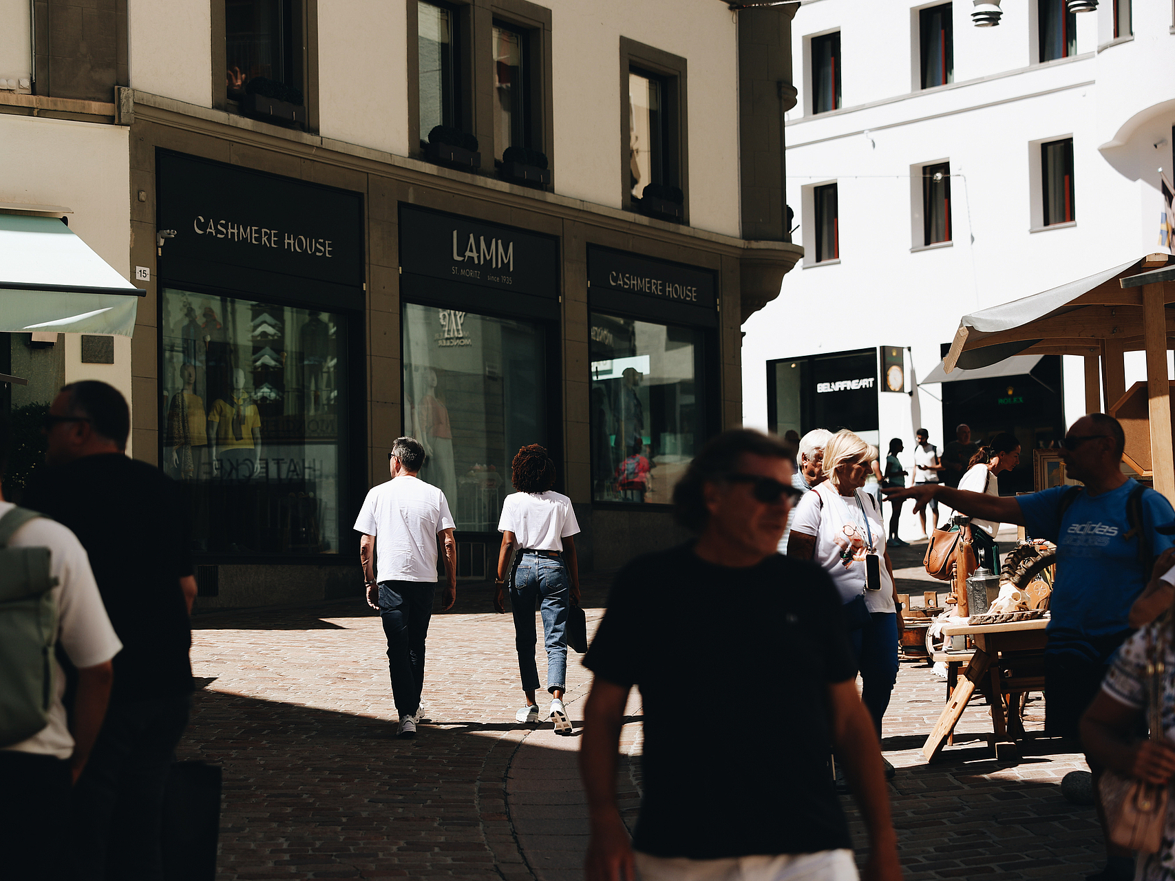 Einkäufer in St. Moritz Fußgänger schlendern auf einer sonnigen Straße an Luxusboutiquen in St. Moritz vorbei.