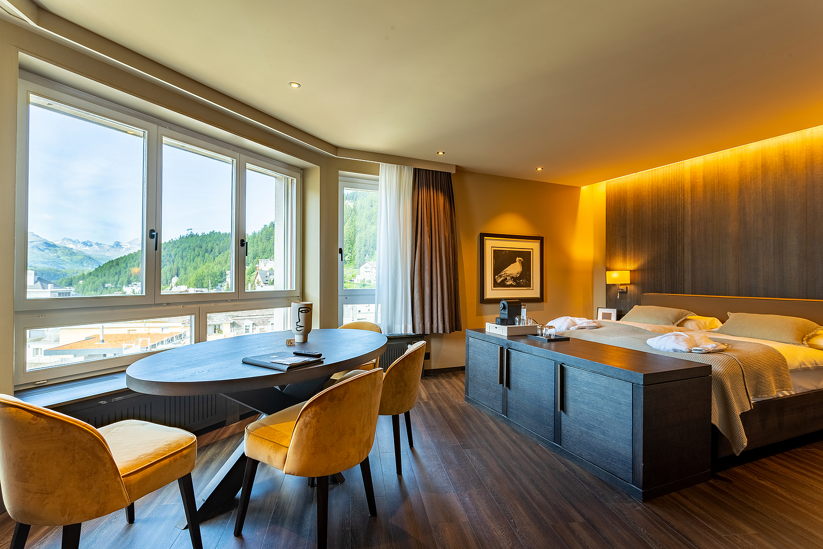 Luxuriöses Hotelzimmer mit Doppelbett, Esstisch und Bergblick.