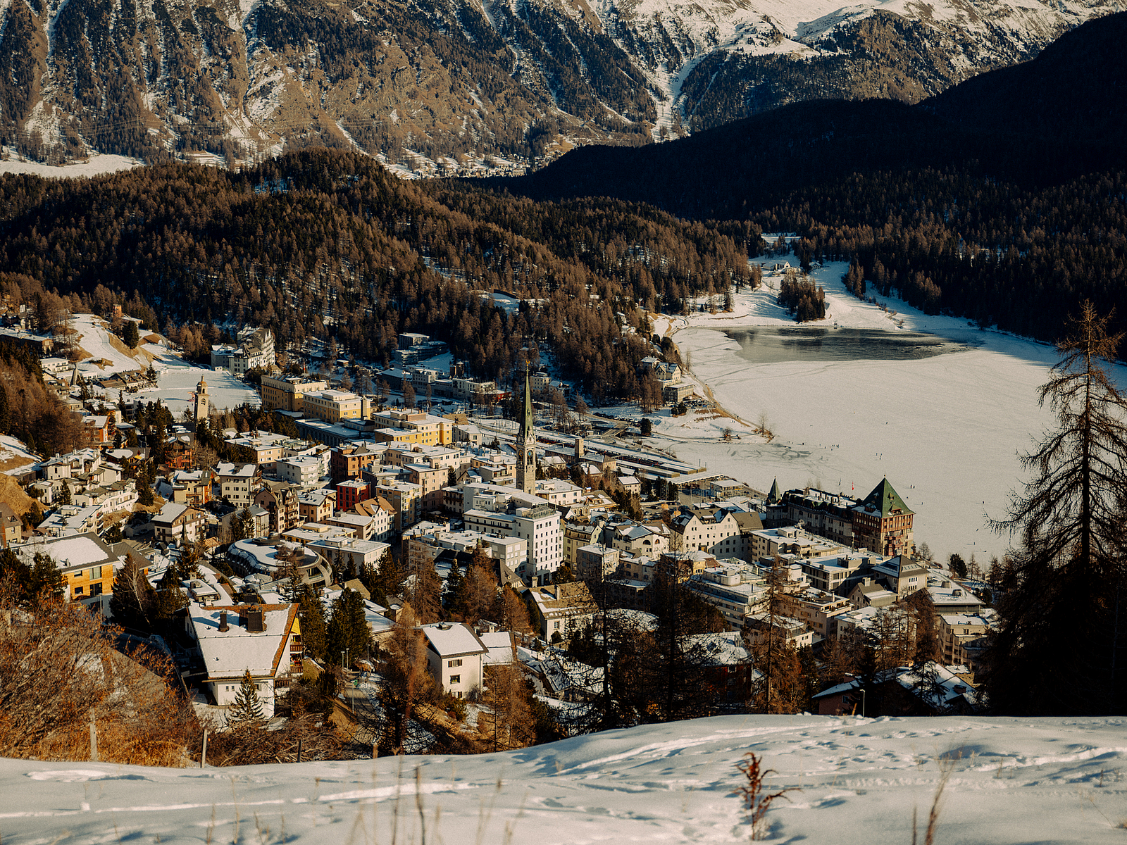 Winterlandschaft von St. Moritz Blick auf St. Moritz mit schneebedeckten Bergen und gefrorenem See.