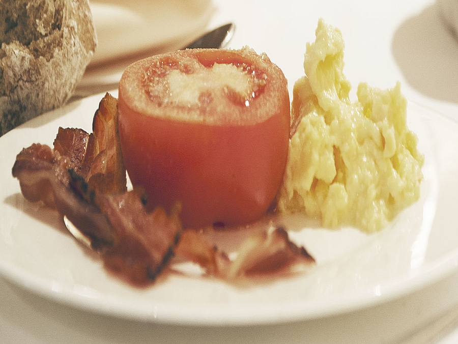 Frühstücksteller mit Ei, Speck und Tomate auf dem Tisch