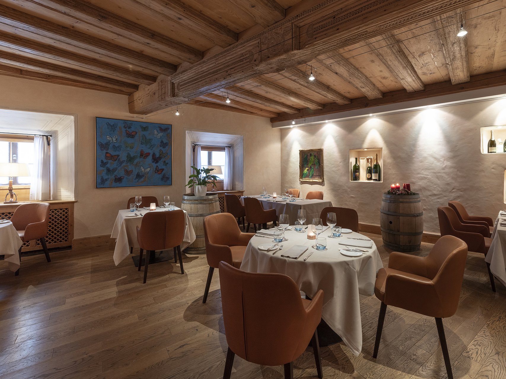 Gemütliches Restaurant mit Holz und Leder Rustikales Restaurant mit Holzbalken, weiß gedeckten Tischen und braunen Ledersesseln