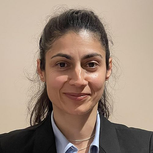 Porträt einer Frau Nahaufnahme einer lächelnden Frau mit dunklem Haar und Blazer.