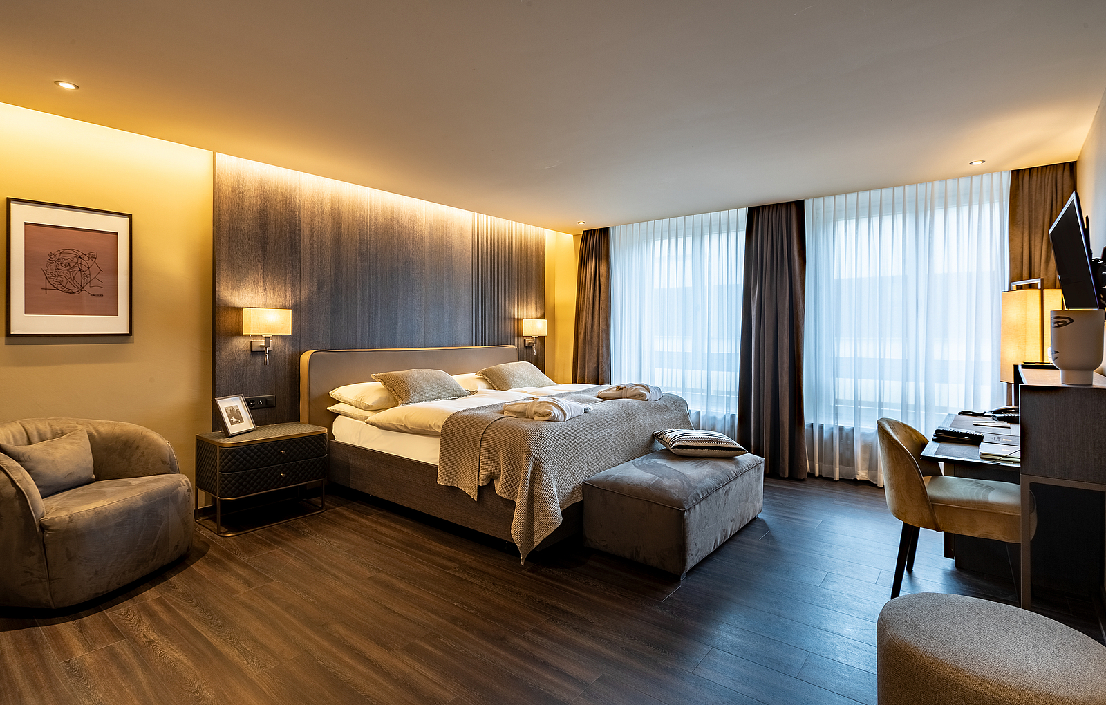 Modernes Hotelzimmer mit Kingsize-Bett, warmer Beleuchtung und Schreibtisch.