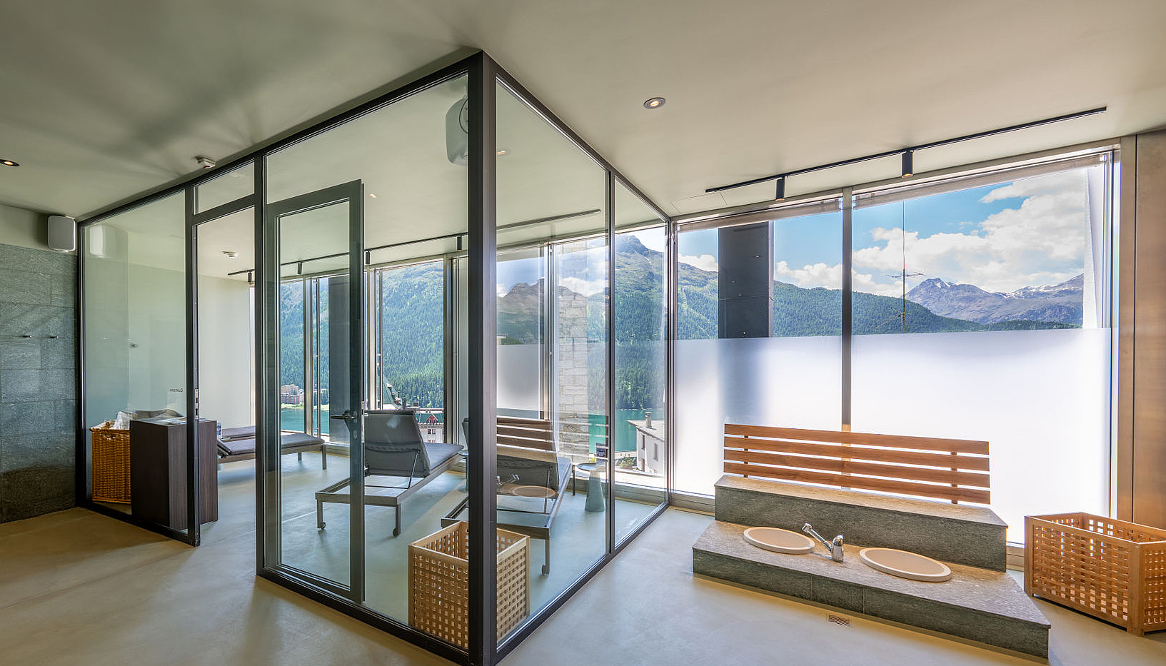 Moderner Wellnessbereich mit Glasruheraum und Fußbecken vor Bergkulisse
