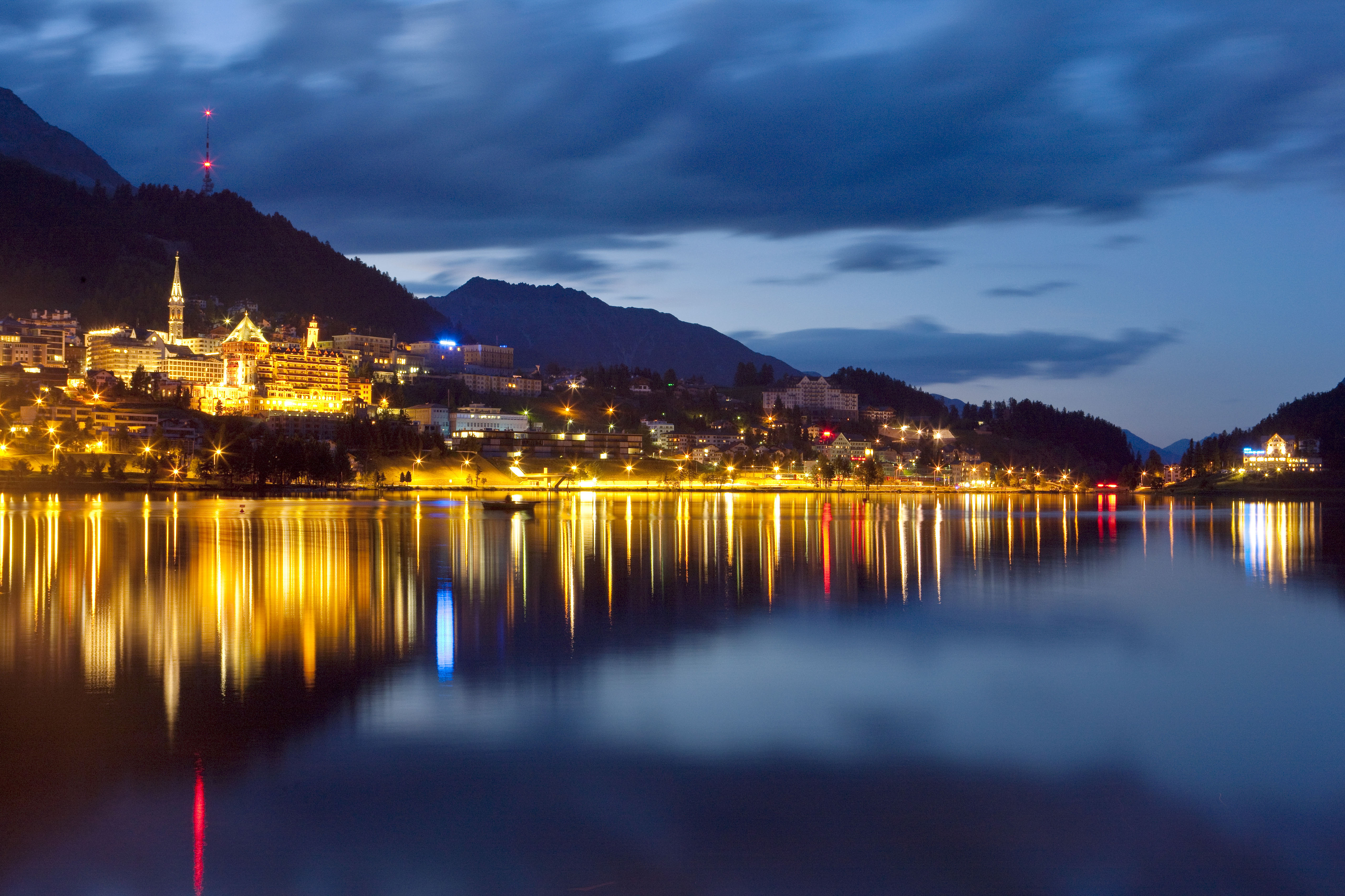 Beleuchtete Stadt St. Moritz und ihre Spiegelung im See bei Dämmerung
