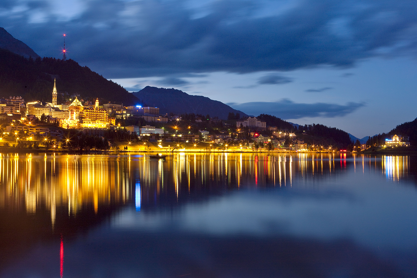 Beleuchtete Stadt St. Moritz und ihre Spiegelung im See bei Dämmerung