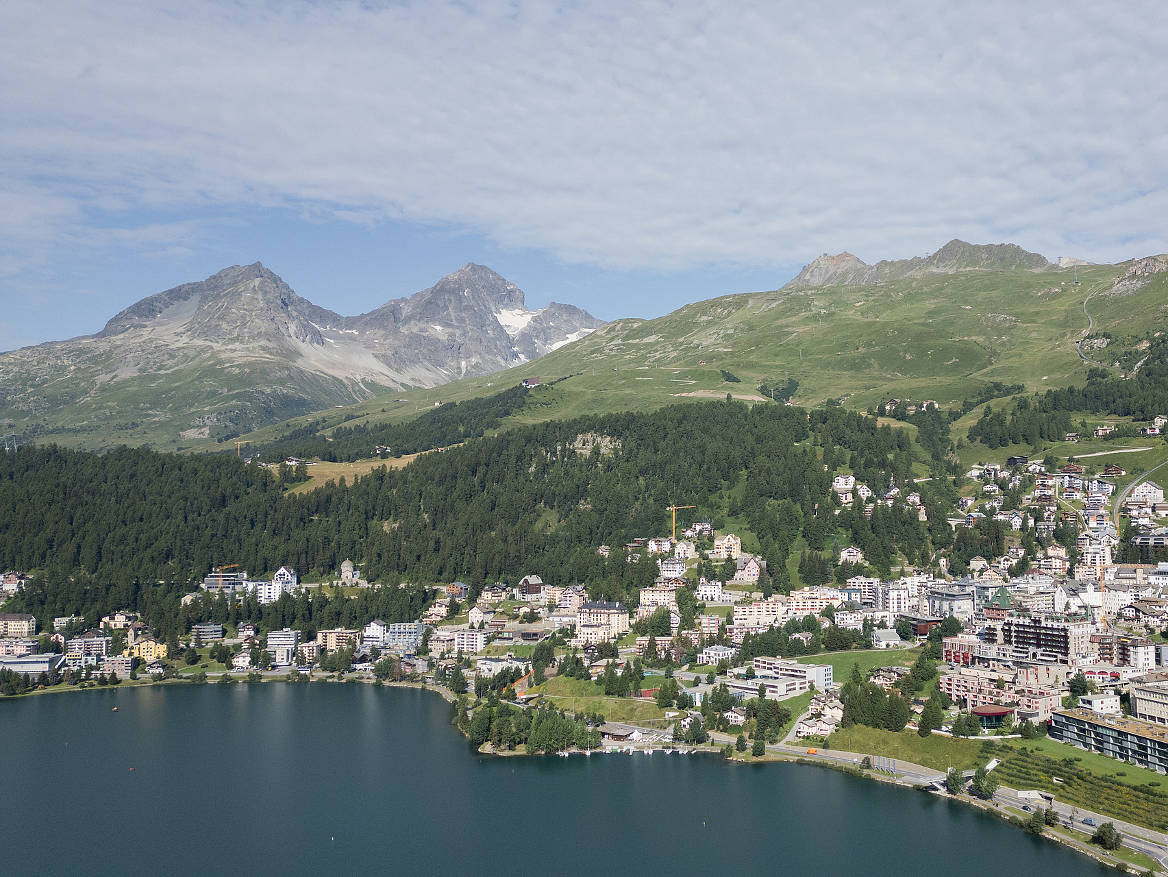Malerisches Alpendorf am See Luftaufnahme eines Alpendorfs an einem See mit Bergen im Hintergrund.