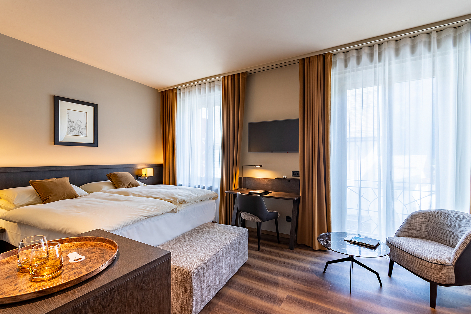 Modernes Hotelzimmer-Interieur Modernes Hotelzimmer mit Doppelbett, Schreibtisch, Sessel und großen Fenstern mit Vorhängen.