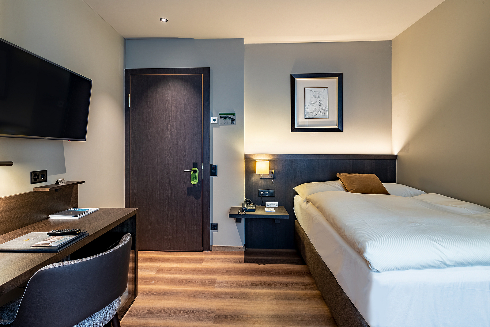 Modernes Hotelzimmer mit Bett, Schreibtisch und TV.