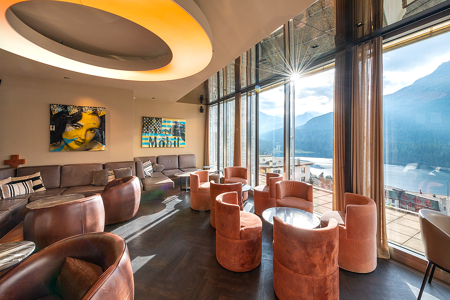 Stilvolle Hotellounge mit Sesseln und Bergblick durch eine große Fensterfront.