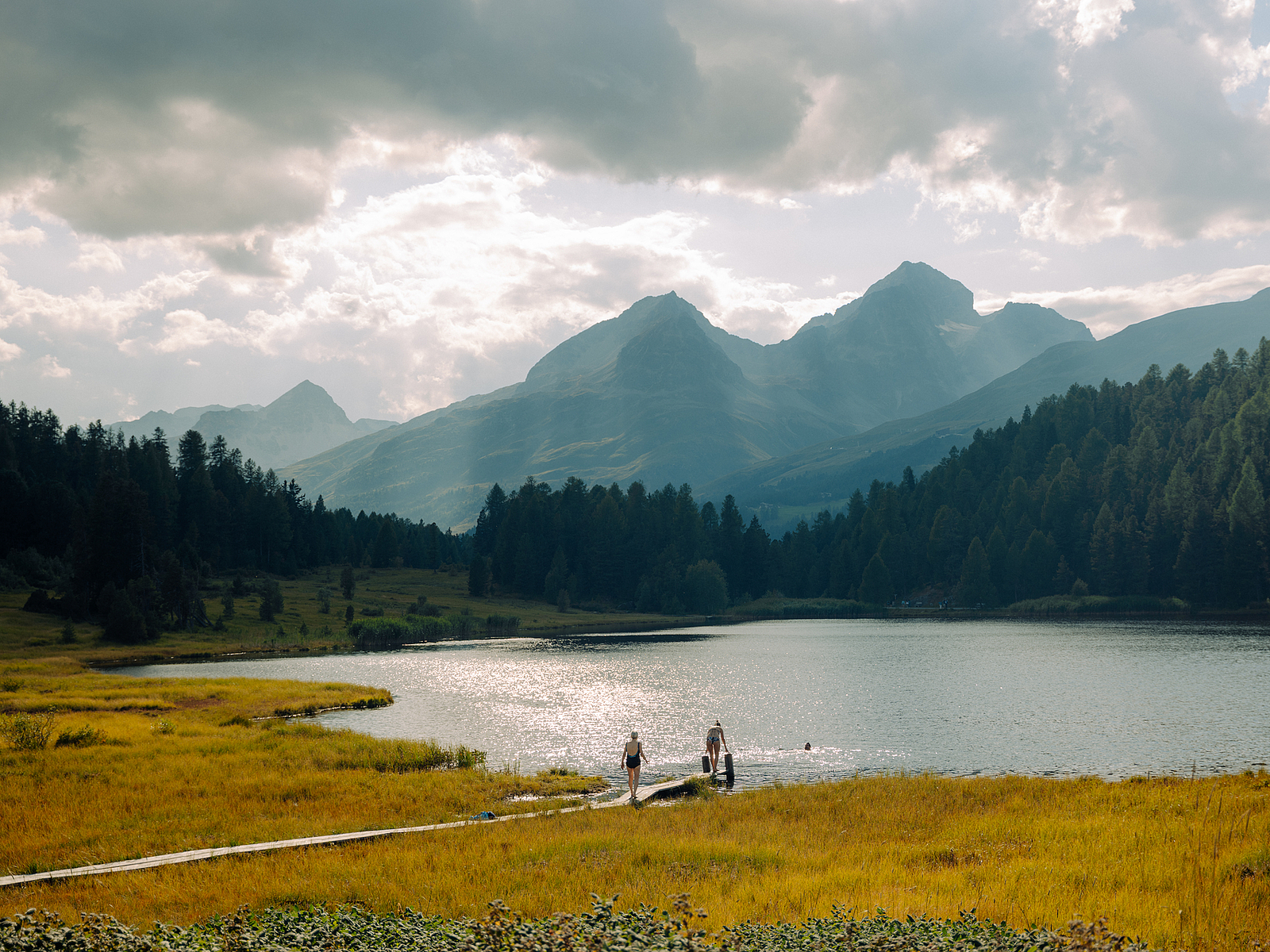 Menschen am Bergsee mit dramatischen Wolken und Gipfeln in der Schweiz