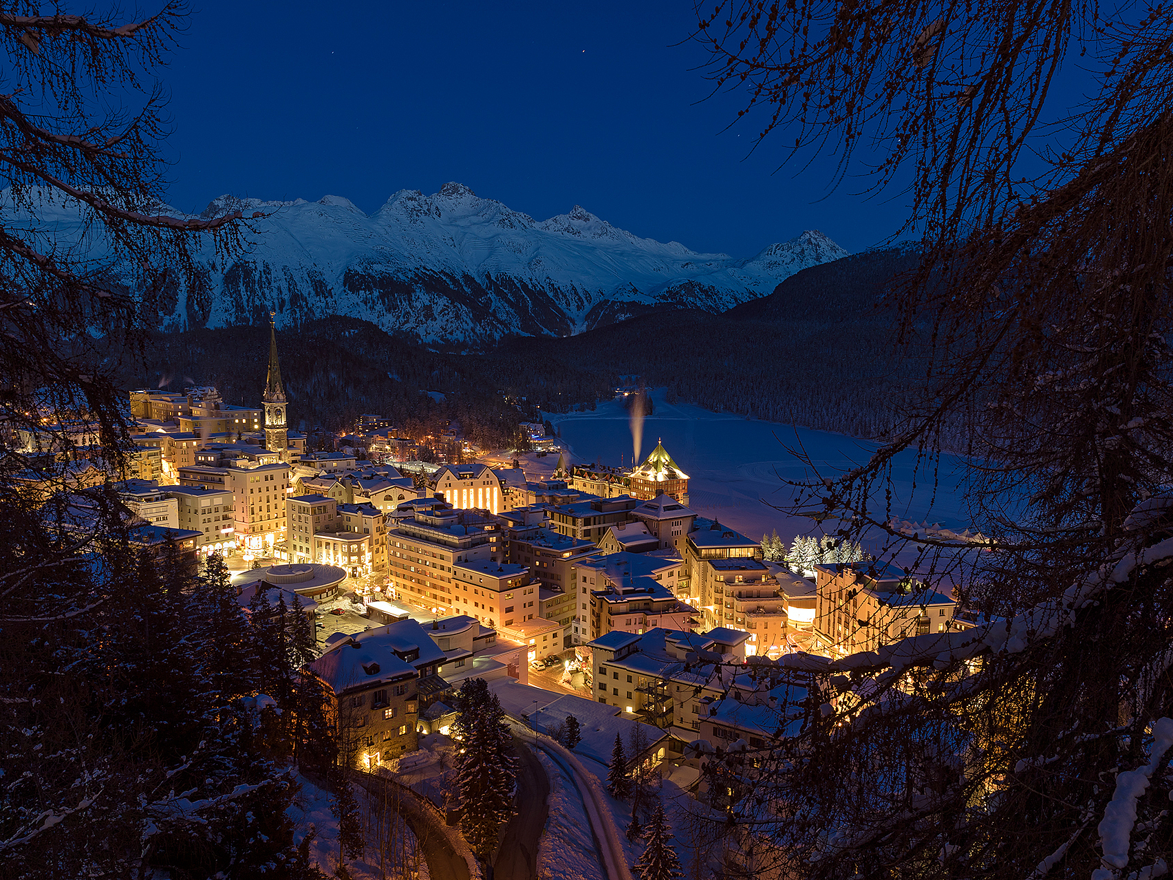 St. Moritz in der Dämmerung im Winter Beleuchtetes St. Moritz und verschneite Berge in der Dämmerung.