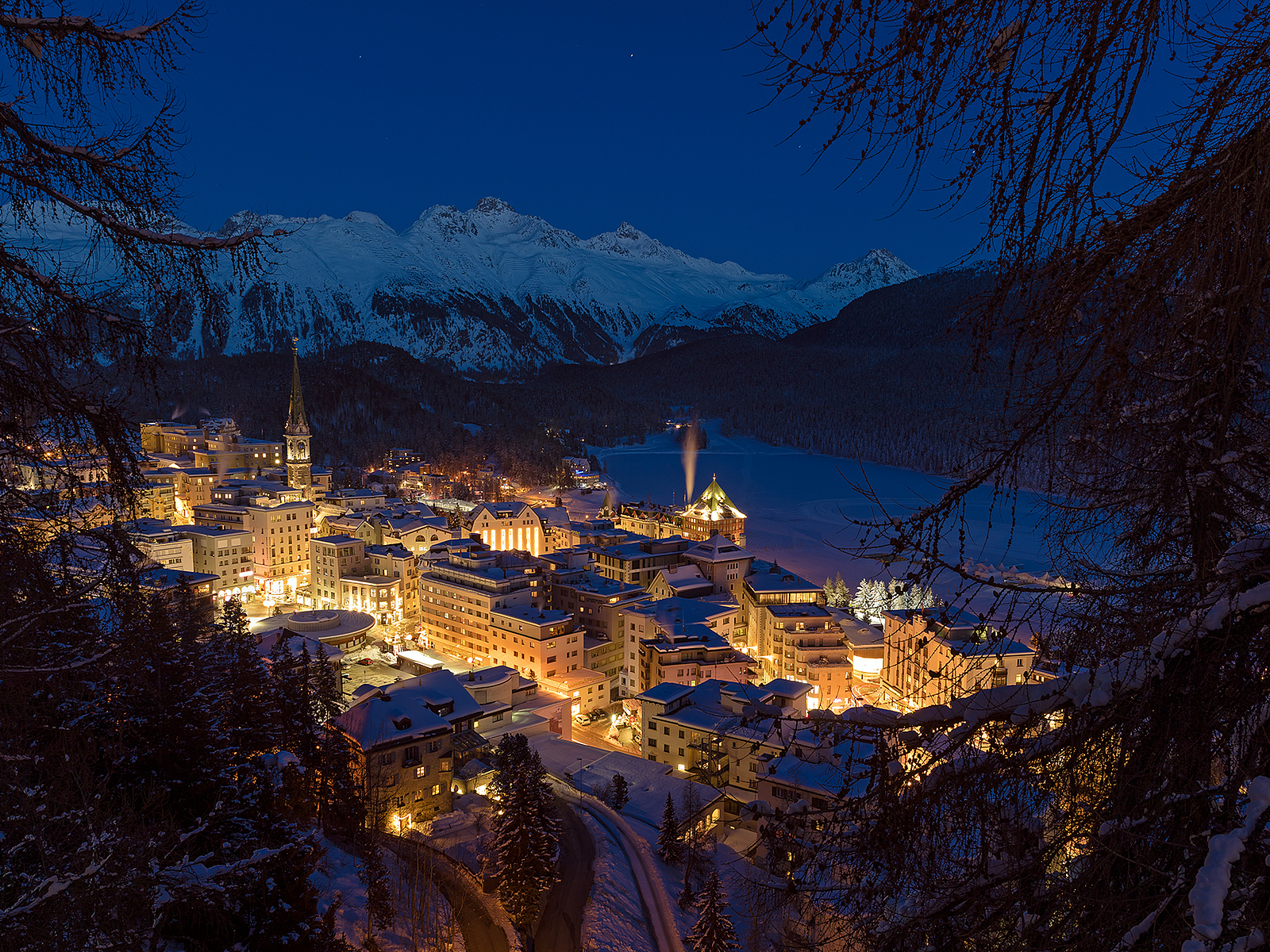 St. Moritz in der Dämmerung im Winter Beleuchtetes St. Moritz und verschneite Berge in der Dämmerung.