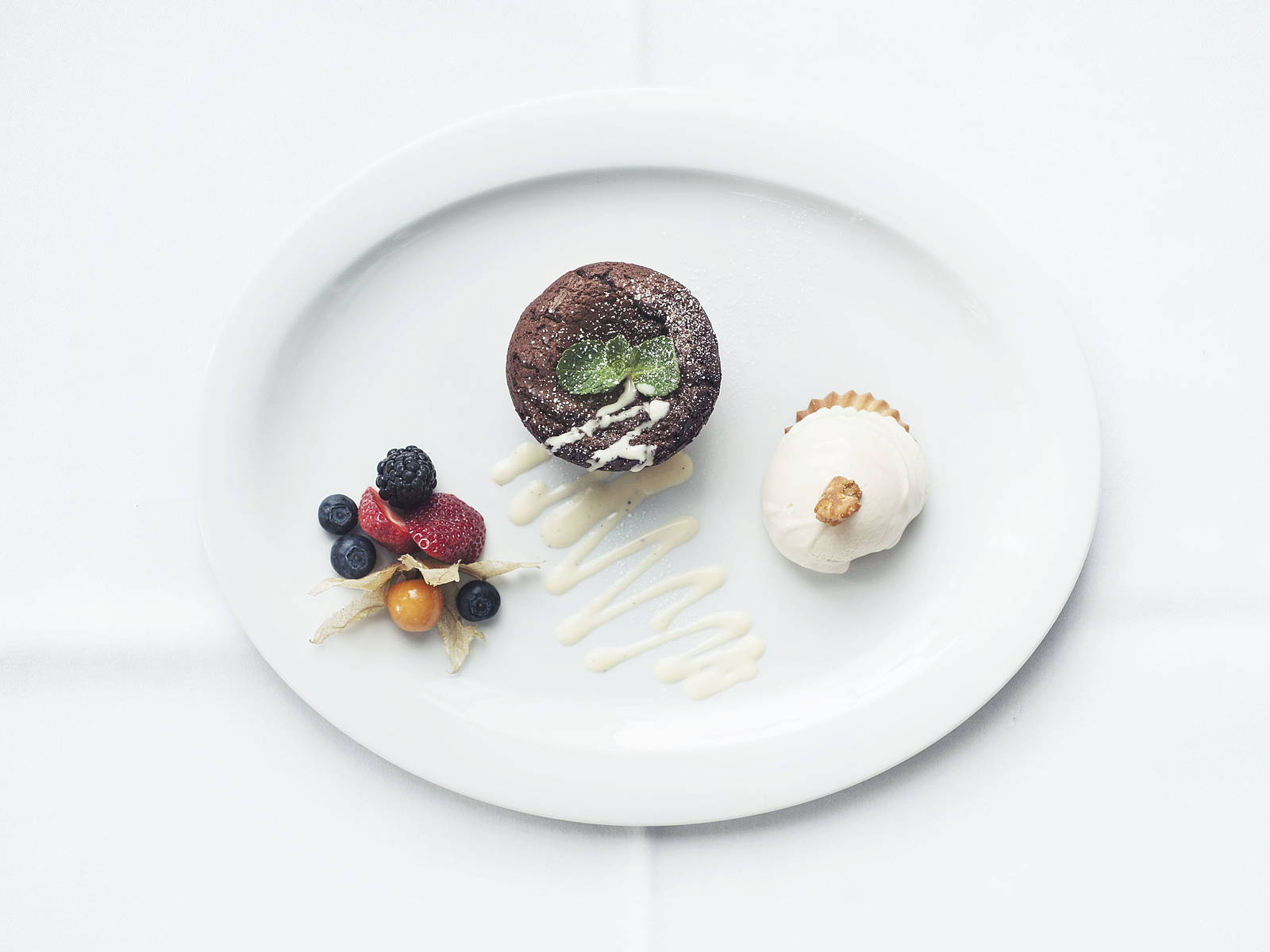 Schokosoufflé mit Eis und Beeren auf einem weißen Teller.