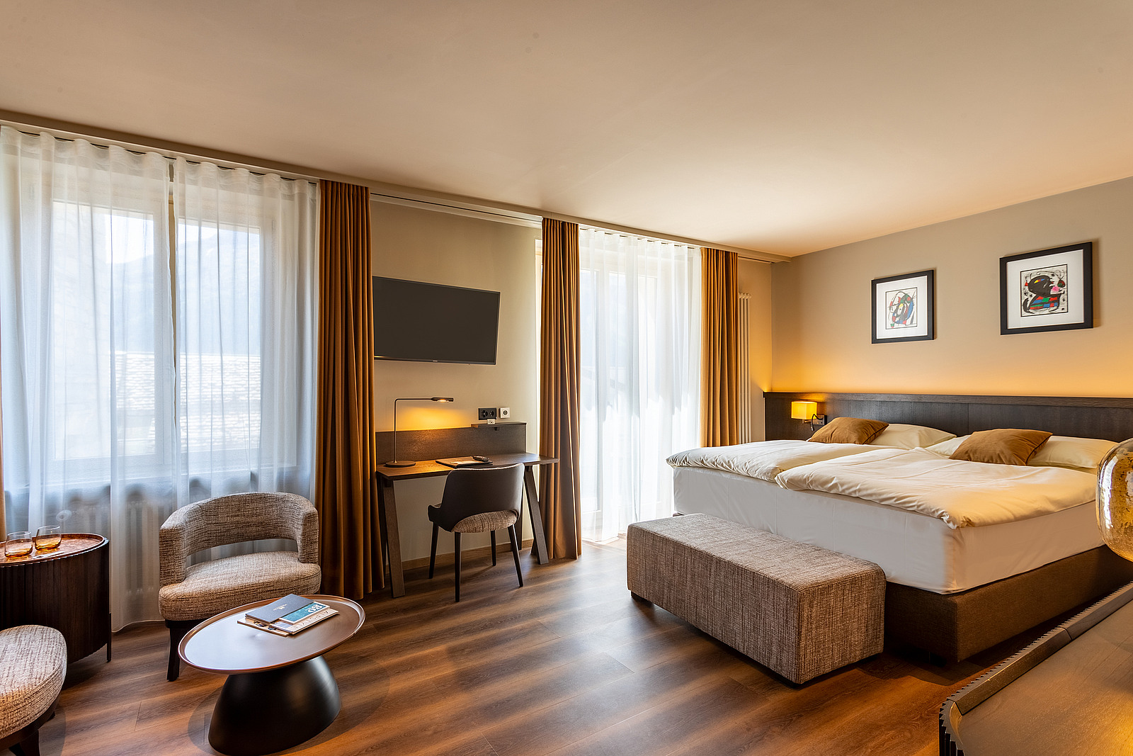 Modernes Hotelzimmer mit großem Doppelbett, Schreibtisch und warmer Beleuchtung