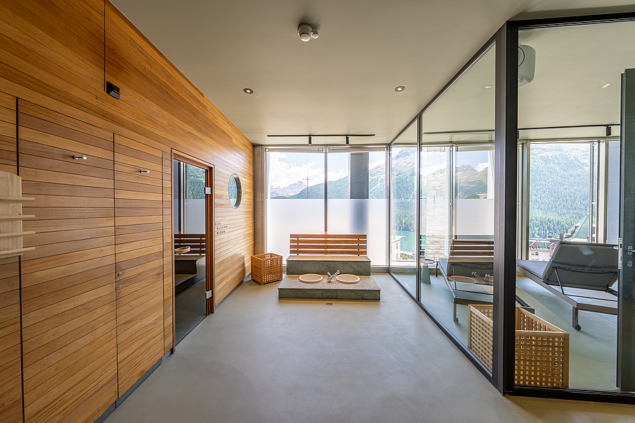 Moderne Spa-Lounge mit Holzverkleidung, Sauna, Fußbädern und Bergblick.