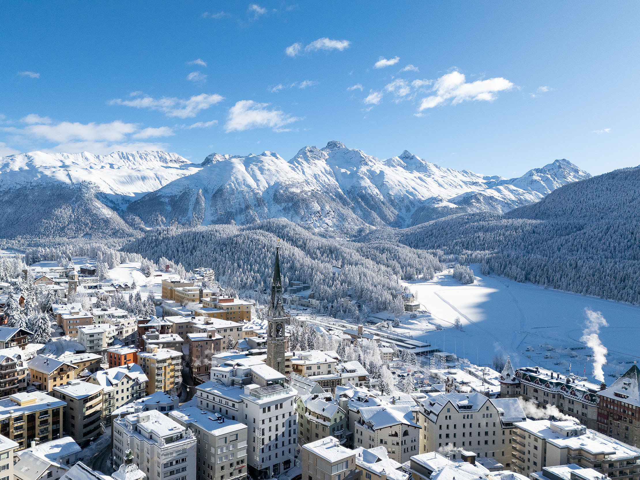 Winterwunderland in den Alpen Verschneite Alpenstadt mit Bergen und zugefrorenem See.