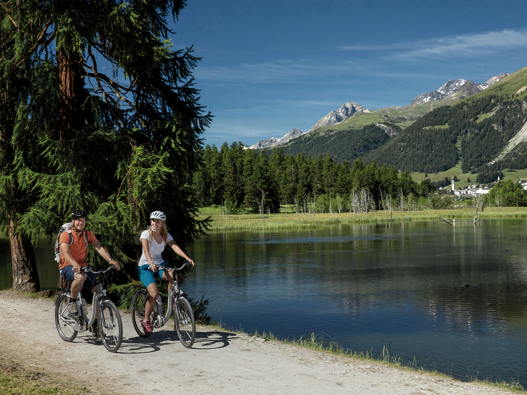 Radfahren am Alpensee Ein Paar fährt E-Bike an einem malerischen Alpensee entlang.