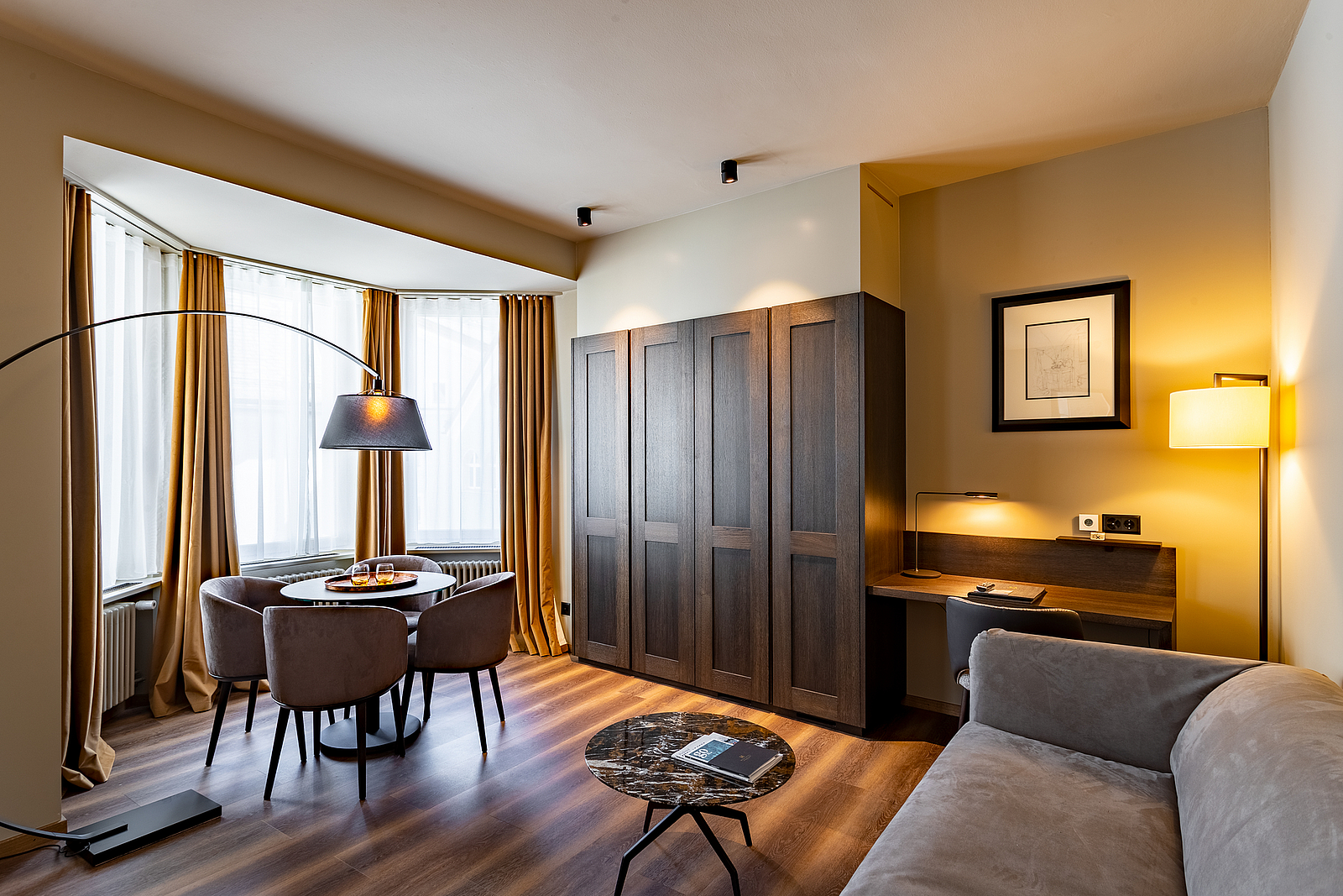 Modernes Hotelzimmer mit Holzkleiderschrank, Sitzecke und warmer Beleuchtung.