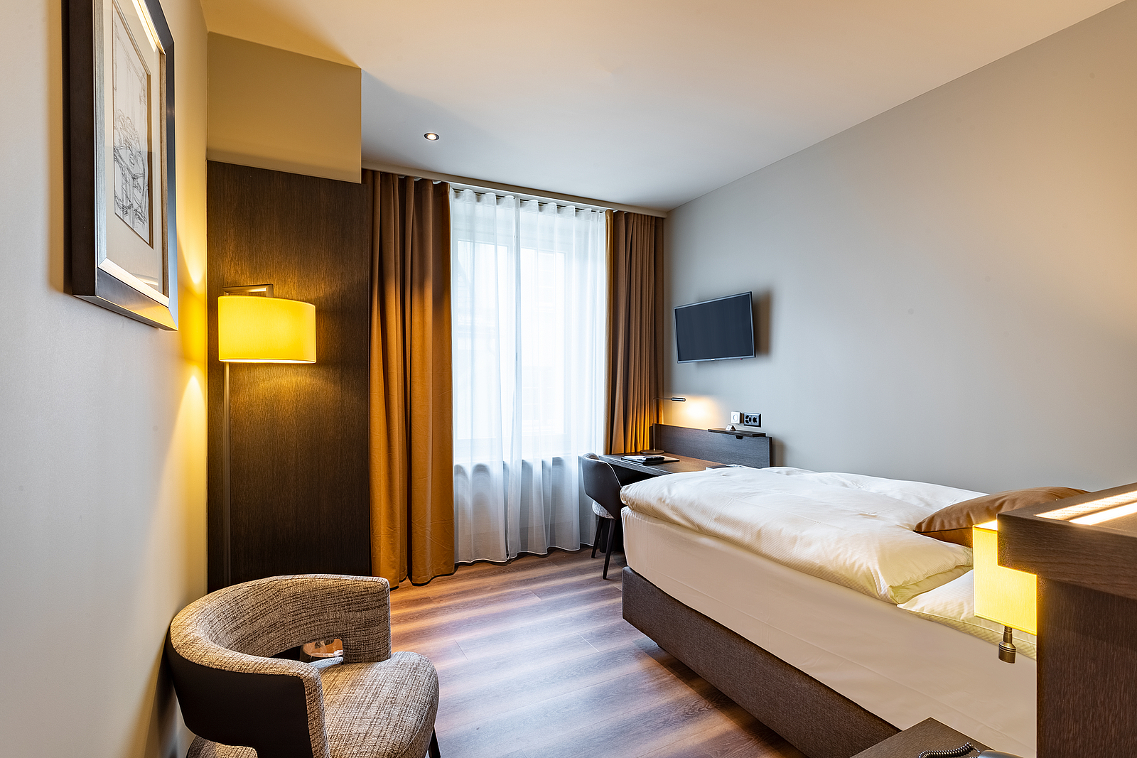 Modernes Hotelzimmer Interieur Modernes Hotelzimmer mit Einzelbett, Sessel, Schreibtisch und warmer Beleuchtung.