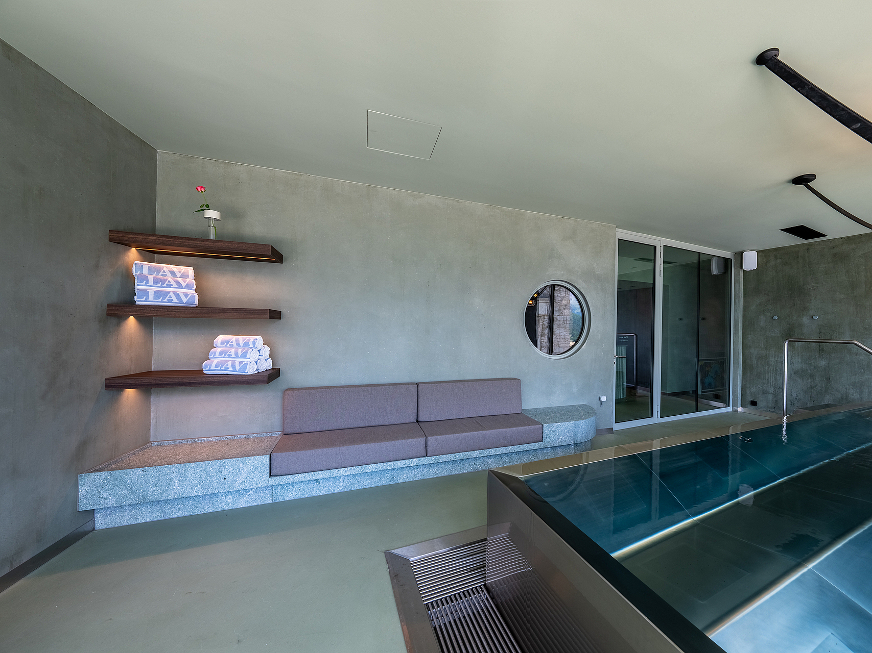 Modernes Hallenbad mit Ruhebereich Modernes Hallenbad mit Edelstahlbecken, Sitzbank und Regalen mit Handtüchern.