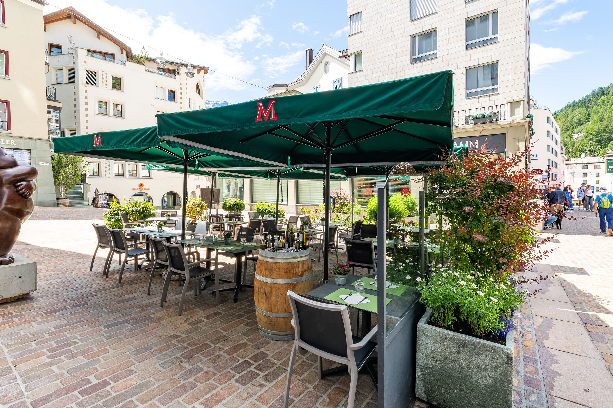 Restaurant-Terrasse in Davos, Schweiz Restaurant-Terrasse mit grünen Sonnenschirmen und Tischen in Davos.